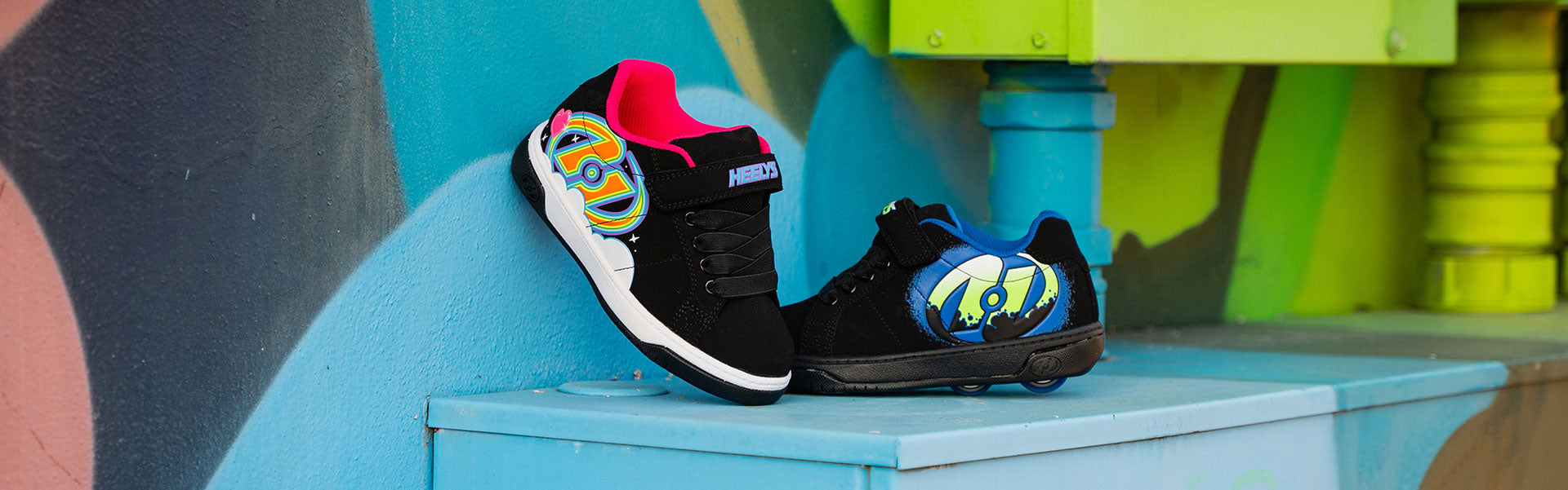 Black Boys Heelys roller shoes with colorful designs on a blue surface