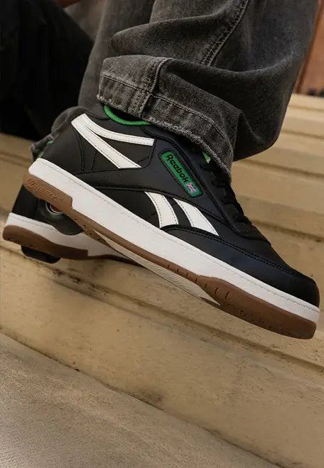 Close-up of a black Reebok Heelys shoe with white stripes and green accents.