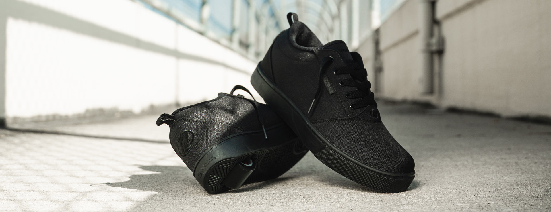 A pair of Heelys Pro 20 in Triple Black, photographed on a concrete walkway.