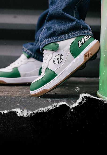 Boy's Heelys. Green and white Heelys roller shoes with brand logos on a concrete surface